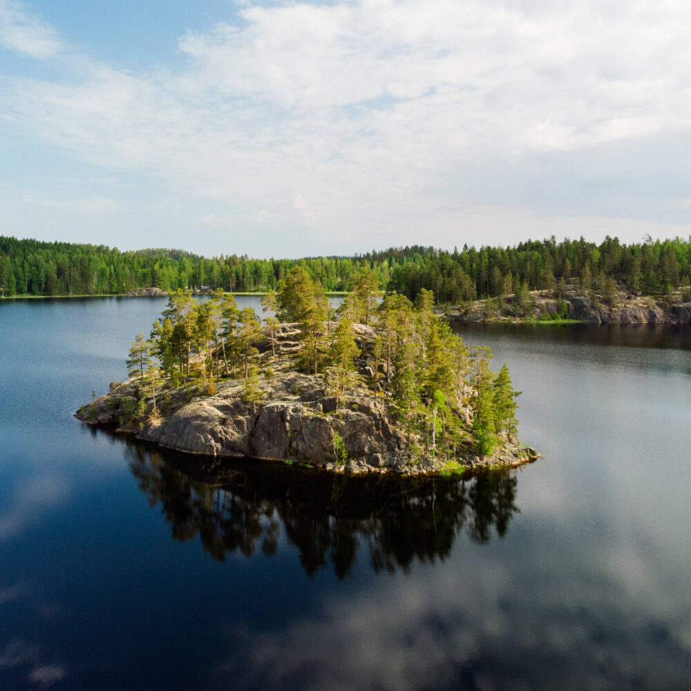 Yläviistosta otettu kuva kallioisesta saaresta keskellä järveä puolipilvisenä kesäpäivänä.
