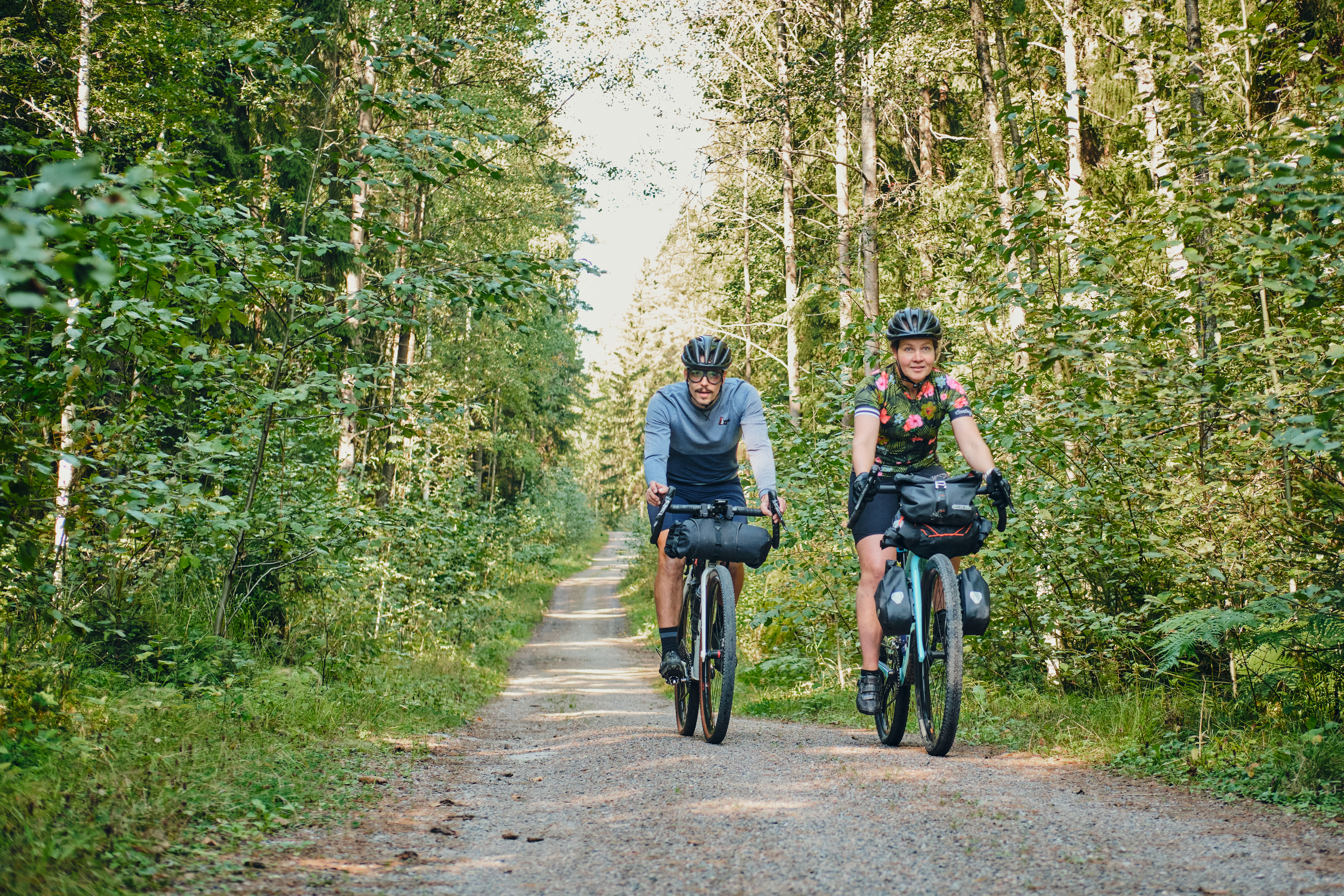 Two cyclists on a small gravel road in the forest