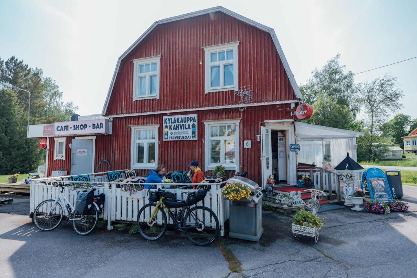 Two cyclists having a coffee break on the terrace of an idyllic wooden village cafe, while their bicycles lean on the terrace