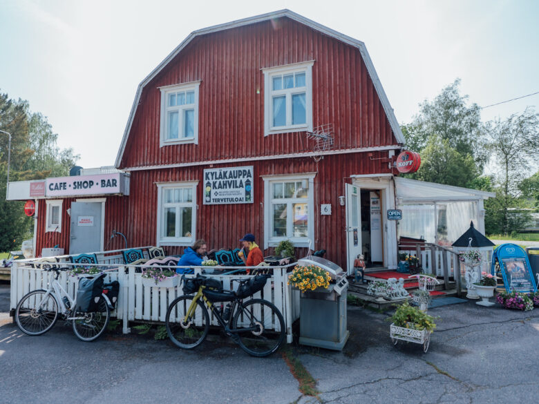 Two cyclists having a coffee break on the terrace of an idyllic wooden village cafe, while their bicycles lean on the terrace