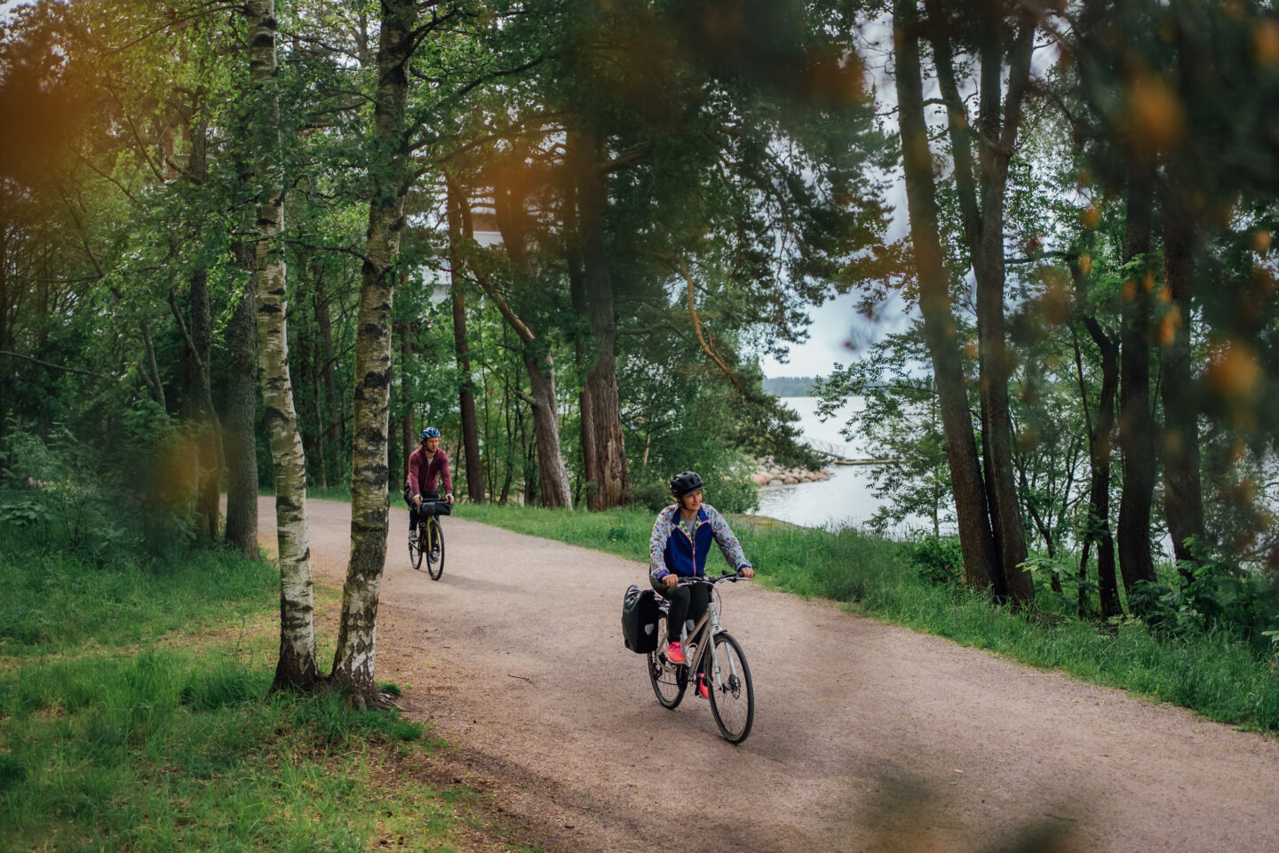 Two cyclists riding a gravel road next to the waterfront