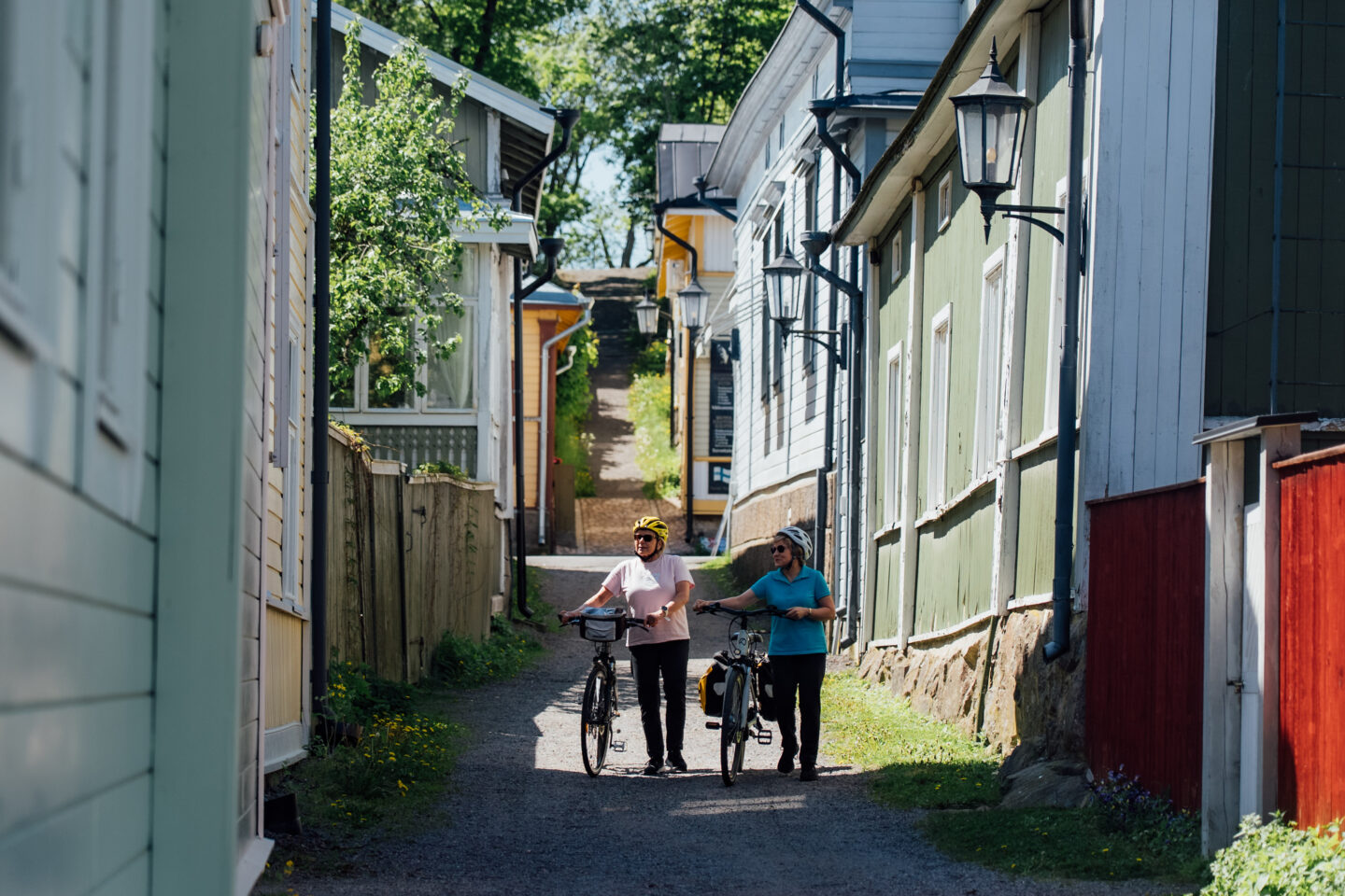 Two cyclists walking their bikes between idyllic old wooden buildings