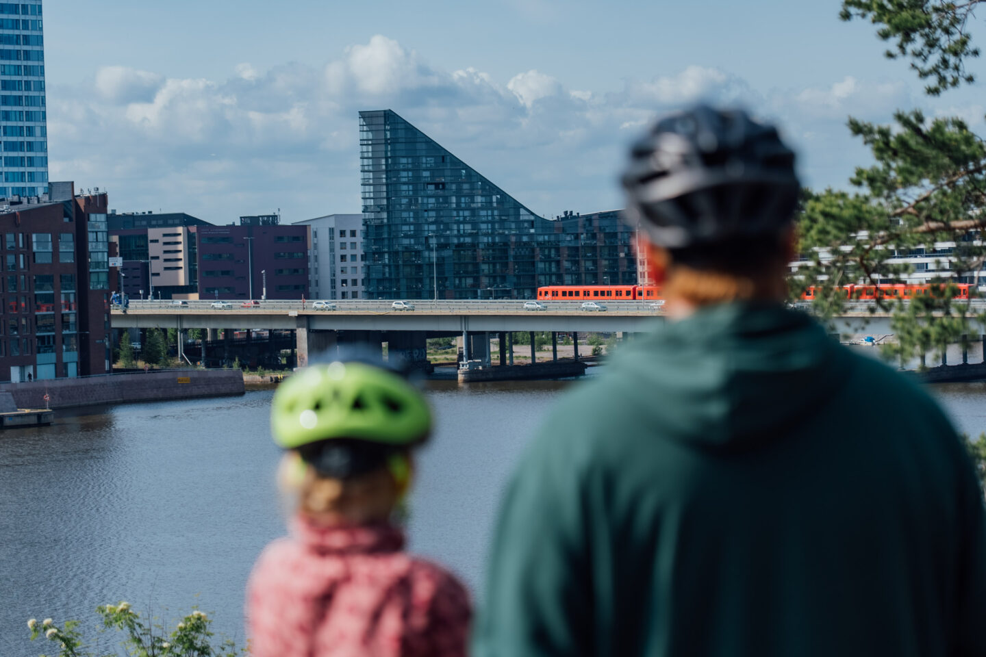 A parent and a child watching an urban view behind a waterfront