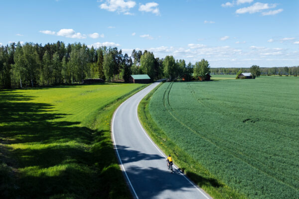 Pyöräilijä maaseutumaisemassa.
