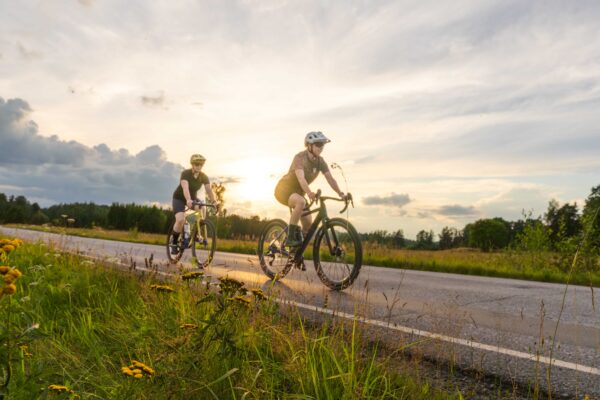 Kaksi pyöräilijää auringonlaskussa maantiellä
