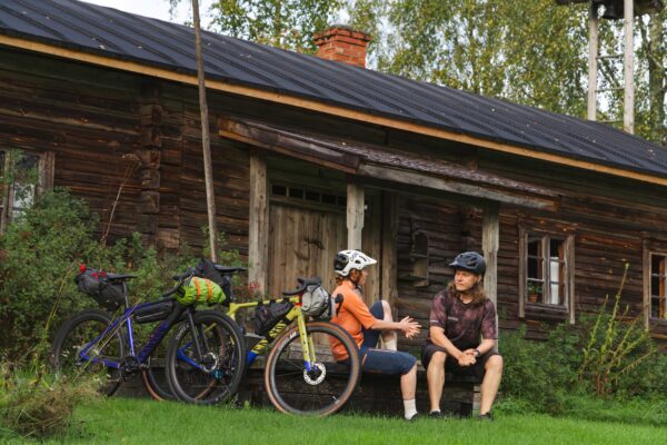 Kaksi pyöräilijää levähtämässä vanhan rakennuksen pihapiirissä